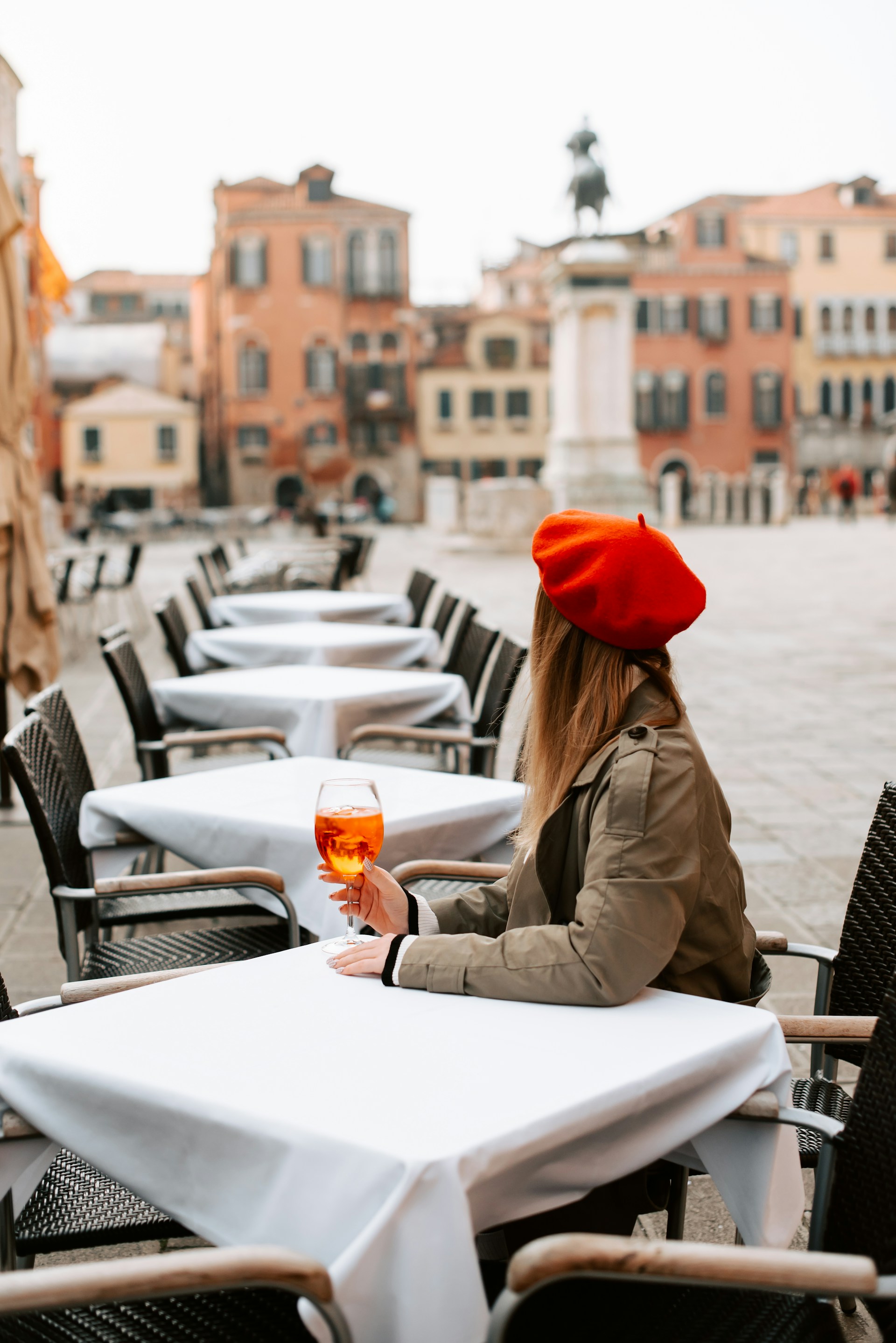 Woman sitting alone at a cafe table in a European square